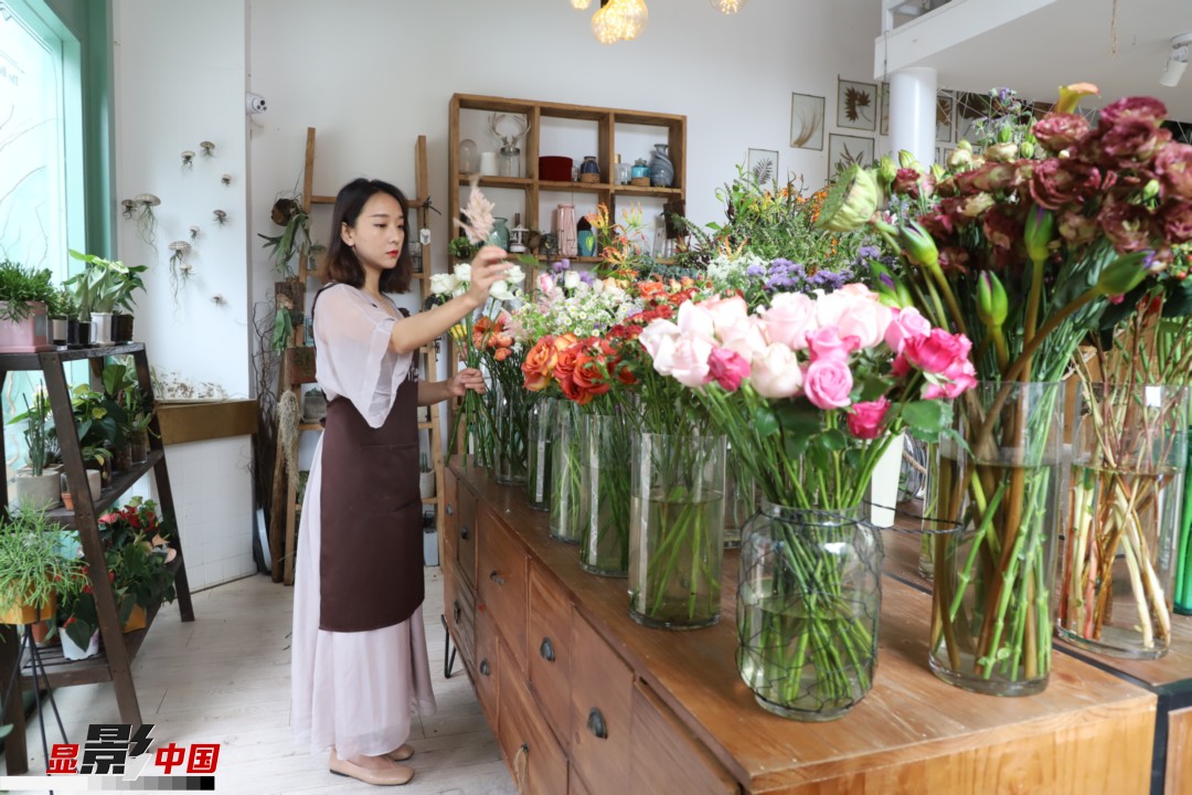 王黎媛是一名河南姑娘，在昆明念完大學(xué)后，就再也舍不下春城的藍天陽光、青山碧水，更舍不下這里的四時繁花，于是就干脆留了下來，成了一名媒體人。2017年的時候又毅然辭去工作，創(chuàng)業(yè)開起了花店，成了都市里的一名“花房姑娘”。圖為王黎媛在自己的花店中整理鮮花。新華網(wǎng) 周亞平/攝 念新洪/文